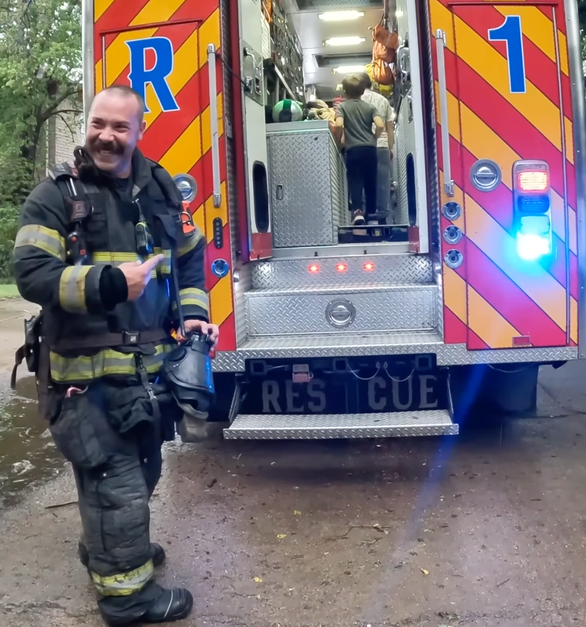 A smiling firefighter beside the open rear of Rescue 1